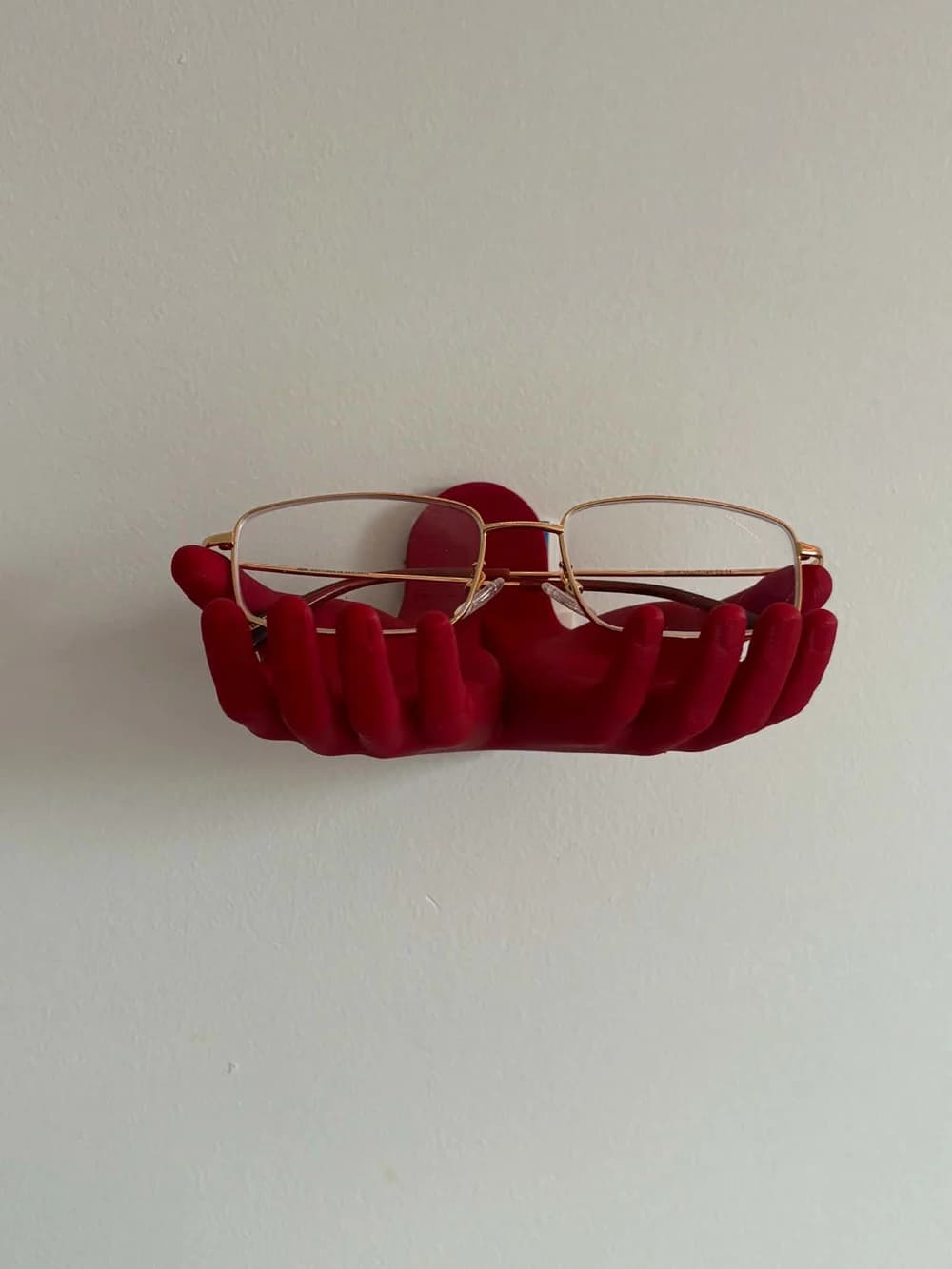 Support mural rouge en forme de mains portant des lunettes